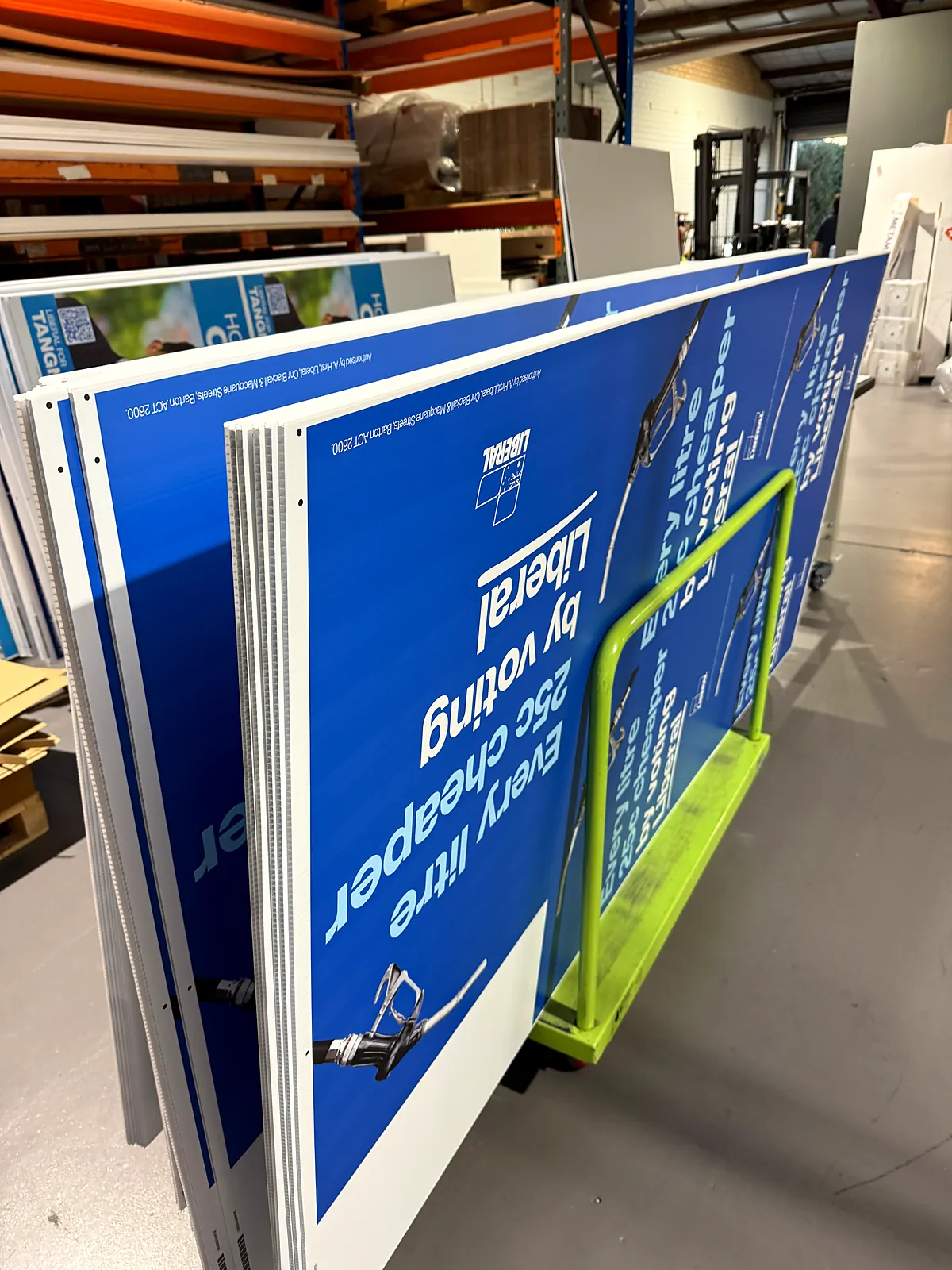 Stack of large printed corflute election signs on a trolley in our Perth warehouse